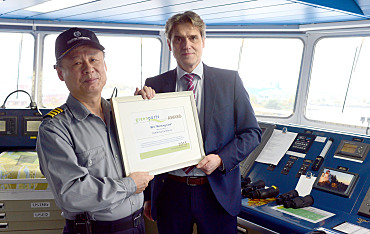 Auf der Brücke: Kapitän Gyeong Sig Lee nimmt die Auszeichnung von bremenports-Geschäftsführer Robert Howe entgegen.