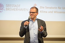 Staatsrat Jan Fries berichtet auf der Jubiläumsfeier über praxisnahe Umwelt- und Klimabildung. Foto: Antje Schimanke