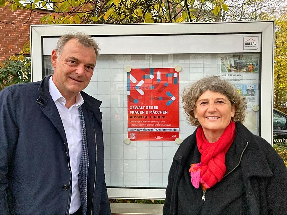 Brebau-Geschäftsführer Bernd Botzenhardt und Landesfrauenbeauftragte Bettina Wilhelm vor einem der Brebau-Schaukästen, in denen Plakate in diesen Tagen auf die Website www.gewaltgegenfrauen.bremen.de hinweisen. 